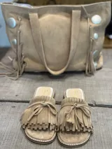 Sandalias bajas color beige de gamuza, con detalle de flecos y lazo en la tira delantera.