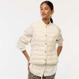 Chaleco acolchado color crema, sin mangas, con cuello mao y cierre frontal con botones a presión. Diseño ligero y corte recto.