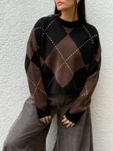 Sweater de punto con diseño de rombos en combinación de colores negro y marrón. Presenta cuello redondo, mangas largas y un calce relajado.
