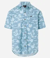 Camisa celeste con estampado de islas, palmeras y flores, de corte relajado, manga corta, cuello inglés, abotonada y con bolsillo en el pecho.