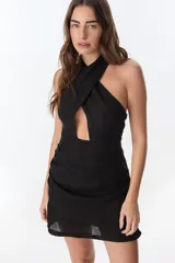 Vestido corto negro con cuello halter cruzado y abertura en el pecho. Corte ajustado al cuerpo.
