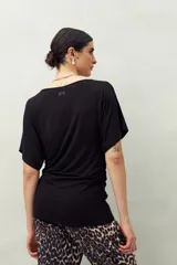 Remera negra de manga corta, confeccionada en modal, con cuello bote y frunces laterales.