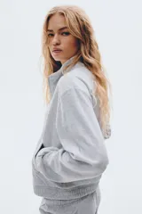 Campera corta de velour gris claro, de corte holgado, con cuello elevado, cierre frontal y bolsillos al bies. Presenta elástico fruncido en puños y bajo.