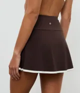 Short pollera deportivo de microfibra, color marrón con borde inferior contrastante en color blanco. Presenta un diseño ajustado y funcional, ideal para actividades físicas.