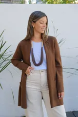 Saco abierto tipo cárdigan de punto en color chocolate, con diseño de corte recto, mangas largas y bolsillos frontales aplicados.