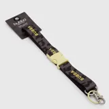 Lanyard de tela con estampado camuflado en tonos grises y negros, con la marca Bubba estampada en color amarillo. Cuenta con una hebilla de cierre de plástico en color crema y un gancho metálico con argolla para llaves.