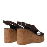 Sandalias de plataforma alta estilo cuña fabricadas en corcho. Presentan tiras cruzadas en el empeine de gamuza color marrón oscuro y cierre mediante pulsera con hebilla metálica al tobillo.