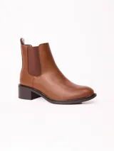 Bota tipo Chelsea color marrón, con paneles laterales elásticos, punta redondeada y taco cuadrado bajo.