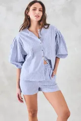 Camisa celeste a rayas verticales blancas, de corte holgado y mangas 3/4 abullonadas.