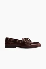 Zapatos náuticos de cuero color marrón con cordones frontales, ojales metálicos dorados y costura de mocasín en la puntera.