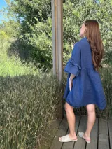 Vestido camisero blanco de lino italiano, con cuello camisero, cierre frontal con botones, mangas cortas con doble volado y bolsillos laterales.