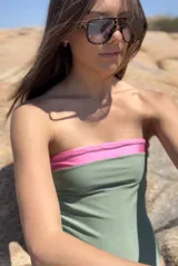 Traje de baño enterizo estilo strapless, con diseño bicolor que combina una franja superior en color rosado y el cuerpo principal en color verde oliva.