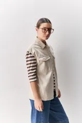 Chaleco de algodón color beige, de calce relajado, con cuello clásico, hombros amplios, cierre frontal con broches metálicos y bolsillos delanteros con solapa.