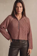 Sweater de punto acanalado color camel, con cuello alto y cierre frontal parcial. Presenta mangas largas con costuras raglán y un corte ligeramente cropped.