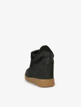 Zapatillas negras con cuña oculta, parte superior de cuero y suela de goma color caramelo.