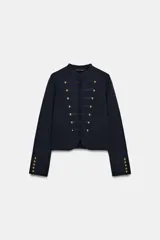 Chaqueta de punto de estilo militar, color azul marino, con cuello redondo y manga larga. Presenta cierre frontal con corchetes ocultos y detalle de botones dorados decorativos en el frente y en los puños.