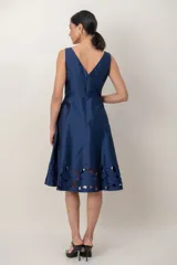 Vestido midi azul marino de tafeta, sin mangas, con escote recto y espalda en V. Presenta un detalle de bordado calado en el ruedo.