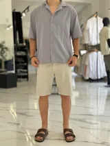 Camisa de lino color beige, de manga corta, con cuello abierto y cierre frontal de botones.