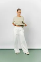 Pantalón blanco de silueta amplia y caída fluida, con cintura alta elastizada y lazo regulable con terminaciones metálicas.