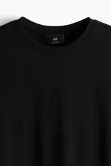 Remera negra de corte ajustado en punto suave de algodón pima, con cuello redondo ribeteado acanalado fino y bajo recto.