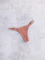 Bottom de bikini colaless color rosado, con tejido acanalado y reguladores laterales con hebillas metálicas.