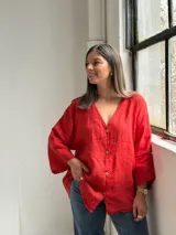 Camisa oversize de lino color rojo, con escote en V, mangas largas amplias y cierre frontal con botones.