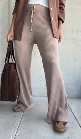 Pantalón de tejido de punto acanalado en color beige, con corte recto y holgado. Presenta cintura elástica con cordón ajustable y terminaciones simples.