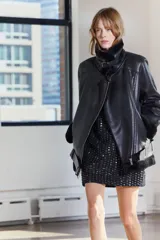 Cazadora negra de Zara Woman Collection, con cuello solapa y manga larga. Tiene bolsillos con cremallera en el delantero, interior de borreguillo combinado a tono y bajo con cinturón ajustable con hebilla metálica. El cierre es frontal con cremallera.