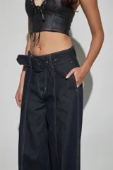 Jean de denim azul oscuro con diseño de tiro alto, piernas anchas de corte recto y costuras pespunteadas en contraste. Incluye un cinturón integrado con hebilla forrada y pasadores anchos.