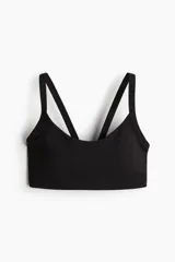 Top deportivo de sujeción media con tecnología SoftMove™ y DryMove™, en color negro, con escote redondo, doble tirante y copas con relleno extraíble.