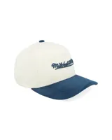 Gorra tipo trucker con corona estructurada en color crema y visera curva en color azul con textura aterciopelada. Presenta el logo de la marca bordado en el frente y detalle lateral.