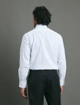 Camisa de vestir de manga larga con cuello rígido y cierre frontal de botones. Presenta un estampado de pequeños puntos azules sobre fondo blanco.