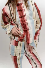 Pantalón de gabardina de tiro medio con diseño de rayas verticales en tonos rosado, rojo, celeste, beige y negro. Cuenta con bolsillos frontales aplicados y cierre con botón.