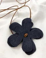 Gargantilla con dije de flor de cuero color negro y cordón de cuero marrón.