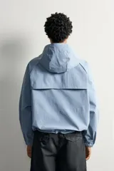 Cazadora cropped fit de tejido técnico negro repelente al agua, con cuello subido, capucha ajustable, bolsillos frontales de plastrón con solapa, mangas largas con puños elásticos y bajo ajustable con cordón.