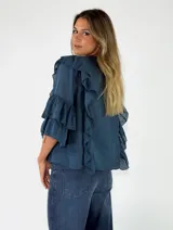 Blusa blanca de manga corta abullonada con volados en cascada y cierre delantero con cordones para atar.
