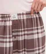 Pantalón de pijama de franela con estampado de cuadros en tonos marrón y blanco. Presenta un corte holgado, cintura elástica y diseño cómodo ideal para el descanso.