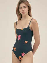 Malla enteriza azul con estampado de flores en tonos naranja y rosa, de breteles finos y escote recto.