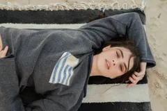 Sweater de hilo de algodón color verde militar, con cuello redondo y manga larga. Presenta un diseño tejido de la bandera uruguaya en el frente.