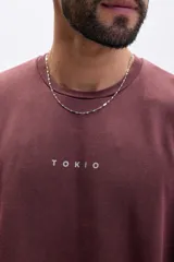 Sudadera color marrón con efecto desgastado, cuello redondo, manga larga con diseño de doble capa y bordes sin rematar. Estampa frontal con la palabra "TOKIO" en blanco.