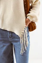 Sweater negro de tejido acanalado, con cuello redondo y un detalle asimétrico en el ruedo inferior con flecos largos.