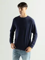 Remera de manga larga con cuello redondo, confeccionada en tejido de algodón con textura tipo mini piqué. Presenta un diseño versátil con puños elásticos en las mangas, ideal para usar como prenda base o como buzo ligero.