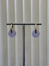 Aros tipo argolla de oro con dije colgante en forma de dona de vidrio color lila.