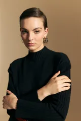 Polera de cuello alto confeccionada en tejido de punto negro, con diseño de textura acanalada en cuello, puños y ruedo, y trama vertical en mangas y espalda.