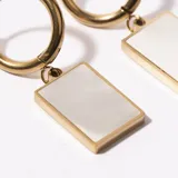 Aros de acero enchapado en oro con forma de argolla y dije rectangular de nácar.