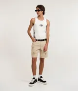 Bermuda masculina de sarga color beige con corte slim, diseño con roturas estilo destroyed y cierre tradicional de botón y cremallera.
