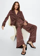 Pantalon palazzo de tejido satinado color bordó con estampado de lunares blancos. Presenta tiro medio, cintura elástica, bolsillos laterales y detalle de ribete en el ruedo.