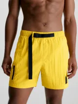 Short de baño amarillo de largo medio, con cintura elástica, cordón ajustable y hebilla con logo. Incluye bolsillos laterales y bolsillo trasero con cremallera.
