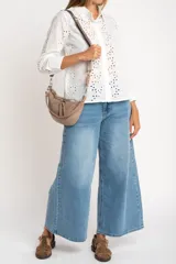 Blusa blanca de manga larga con cuello camisero y bordado tipo broderie anglaise con diseño floral calado.