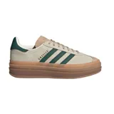 Championes Adidas modelo Gazelle Bold con diseño de plataforma apilada en color caramelo. Confeccionados en gamuza color crema con las icónicas tres tiras laterales y refuerzo en el talón en color verde oscuro.